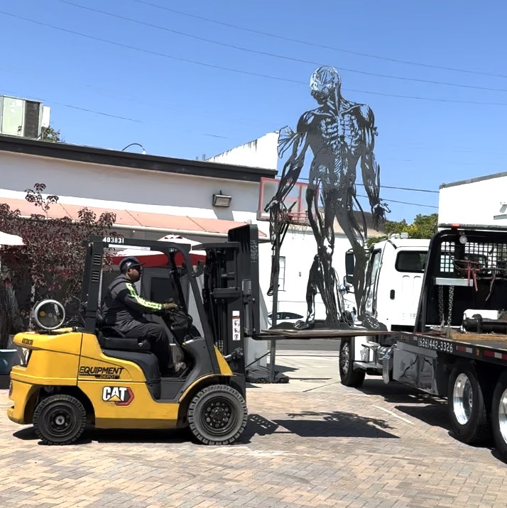 Cor Fabrica being unloaded by forklift from a flatbed truck on arrival at the site for permanent installation, July 24, 2025