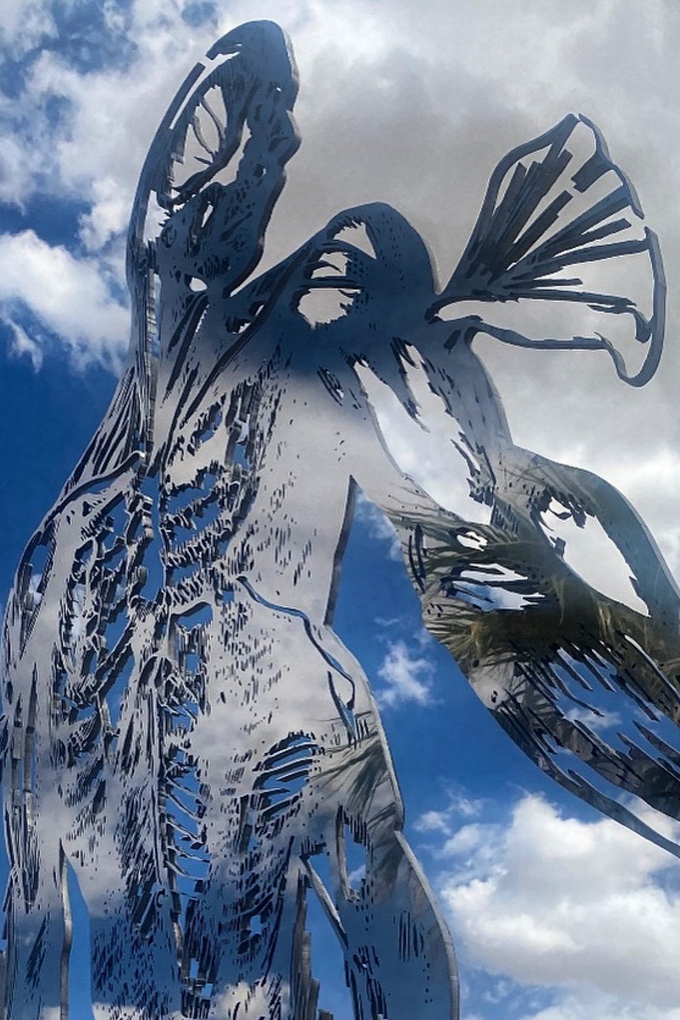 Cor Fabrica, installation view at Chocolate Drop, Twentynine Palms, 2023 — dramatic upward angle, mirror surface reflecting blue cloudy sky