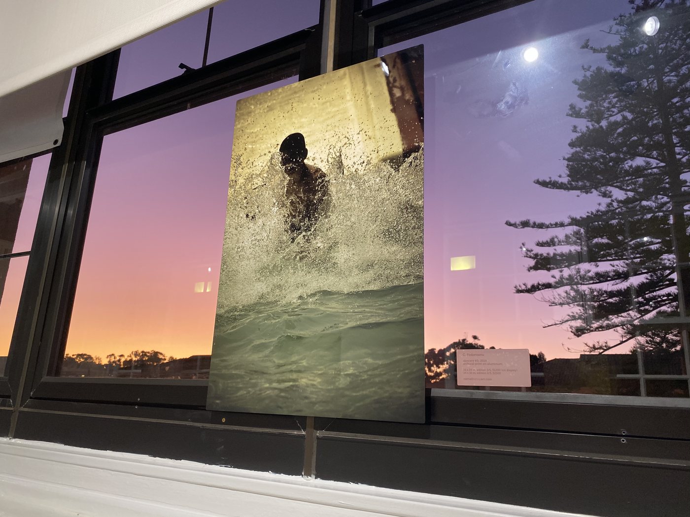 dancers, installation view at Cornel/Henry Art, San Diego, 2019 — a framed photograph of a figure in white spray, the dusk sky and a tree through the windows behind