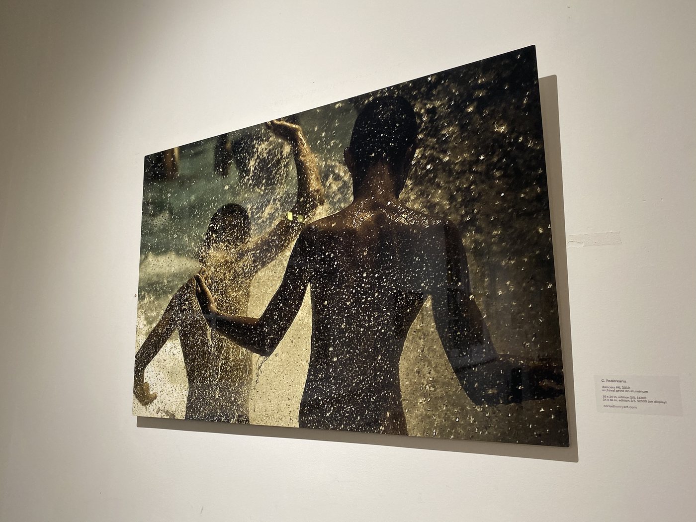 dancers, installation view at Cornel/Henry Art, San Diego, 2019 — a framed photograph of two figures in a gold-lit splash, hung on a white wall