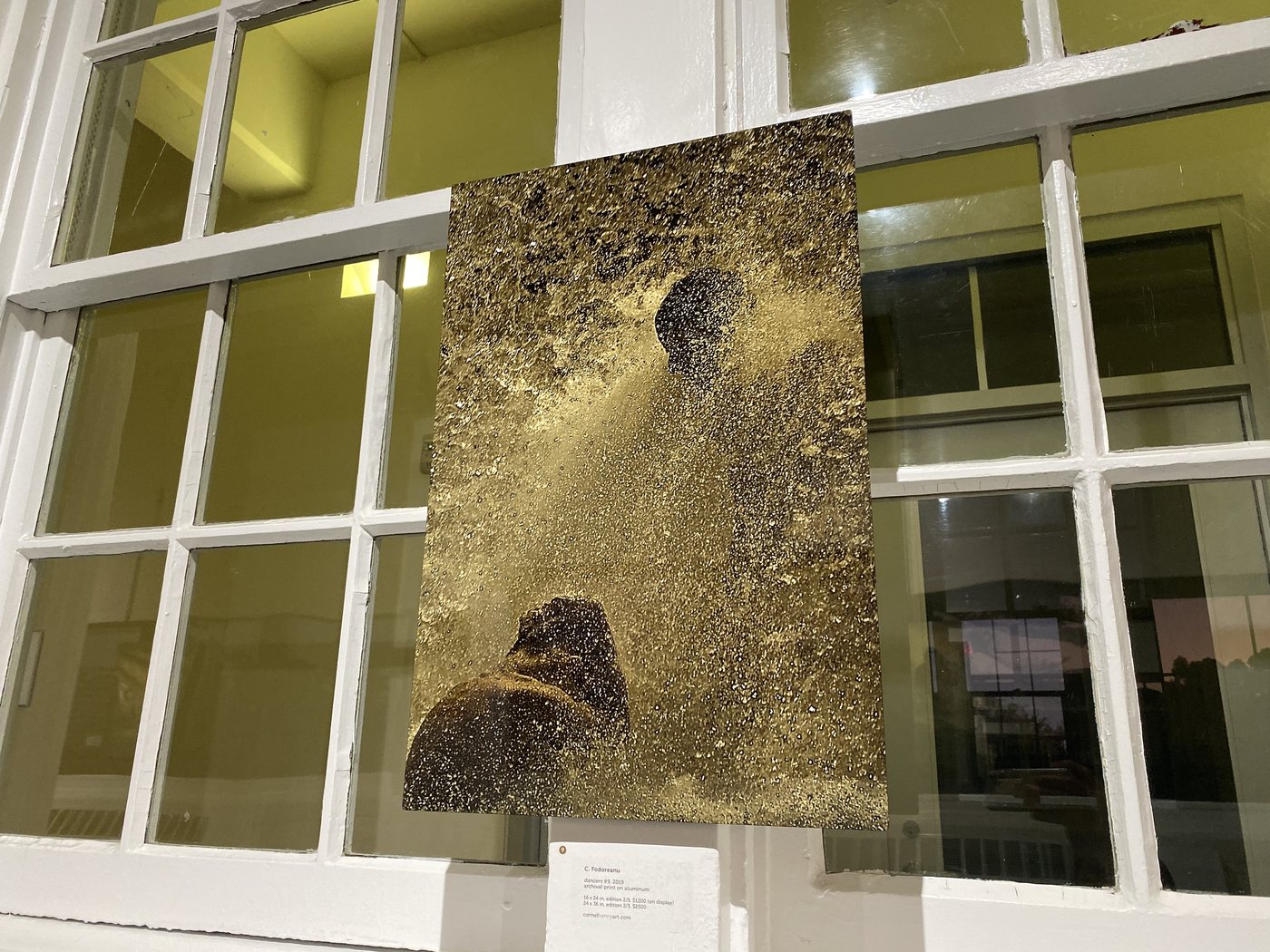 dancers, installation view at Cornel/Henry Art, San Diego, 2019 — a framed photograph of a figure low in a column of gold spray, against the window mullions