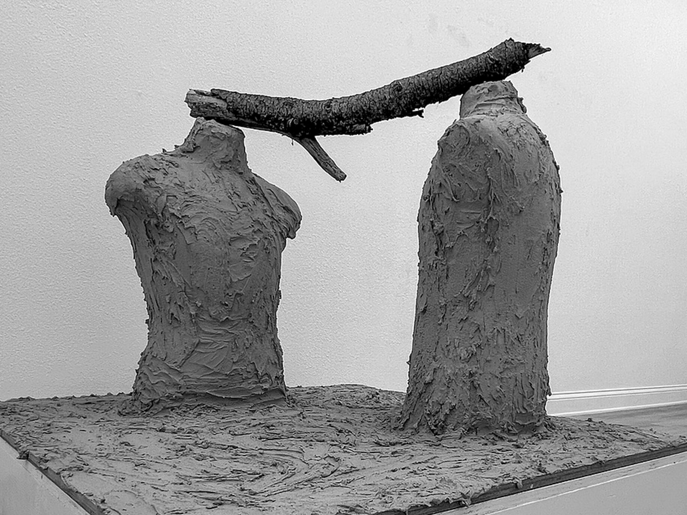 lorem ipsum — two hand-applied cement torsos joined at the shoulders by a barked tree branch, set on a cement-covered pedestal.