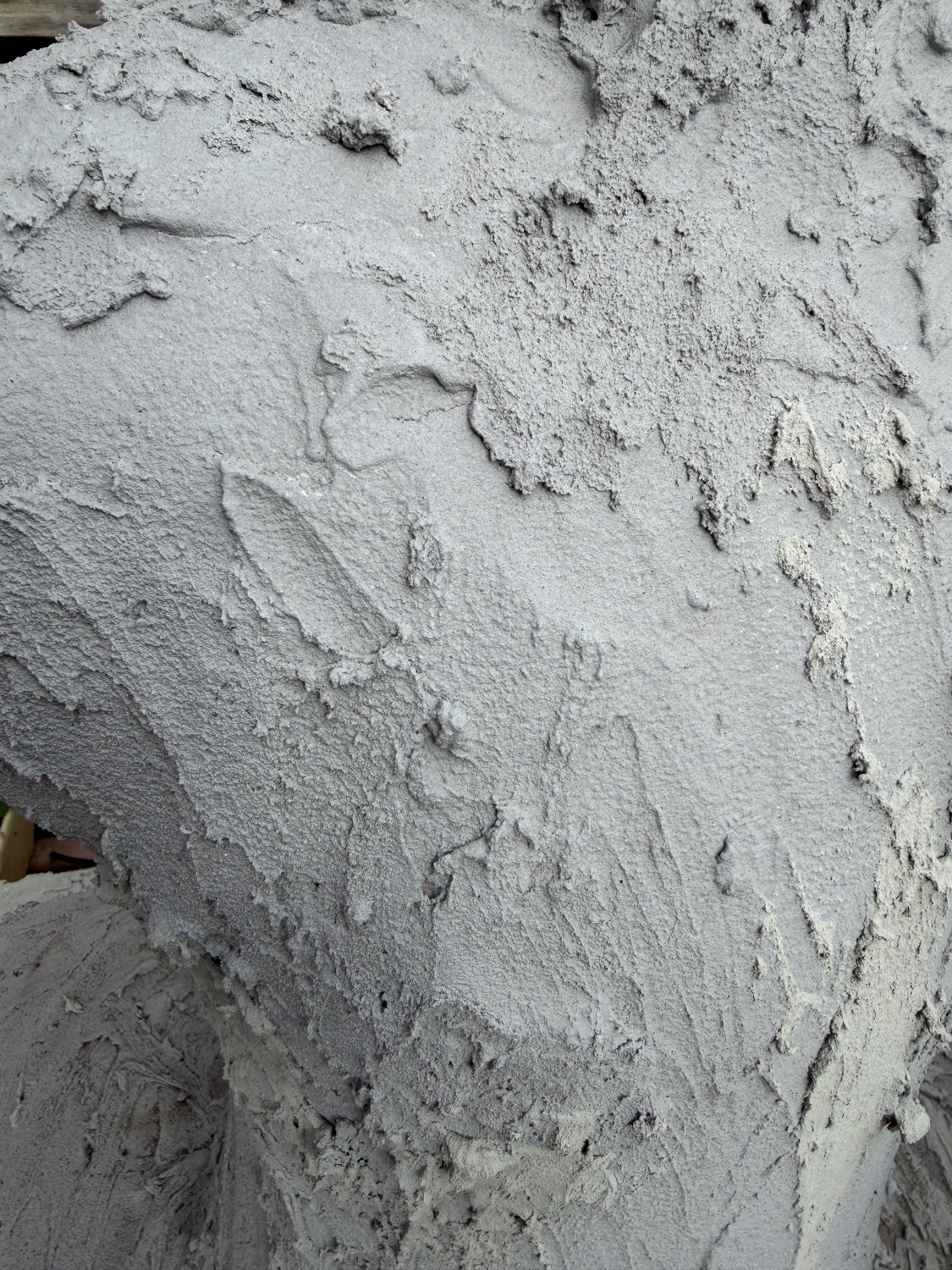 lorem ipsum, surface detail — rough hand-applied cement, top of one of the figures, irregular ridges and pulled peaks