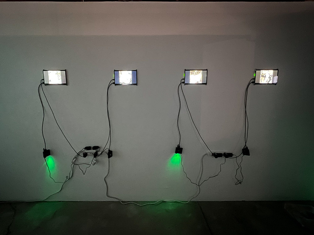 the measure of all things, installation view at The Studio Door, San Diego, 2022 — wall of four small video monitors with cables and indicator lights