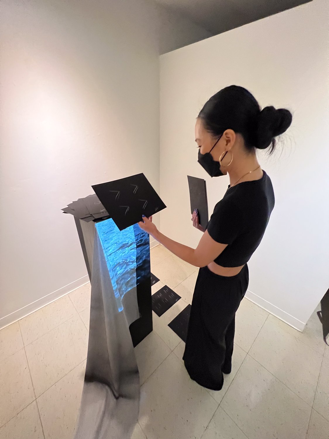 visitor interacting with the take away, lifting cards from the pedestal, Fine Arts Studios, School of Visual Arts, New York, 2022