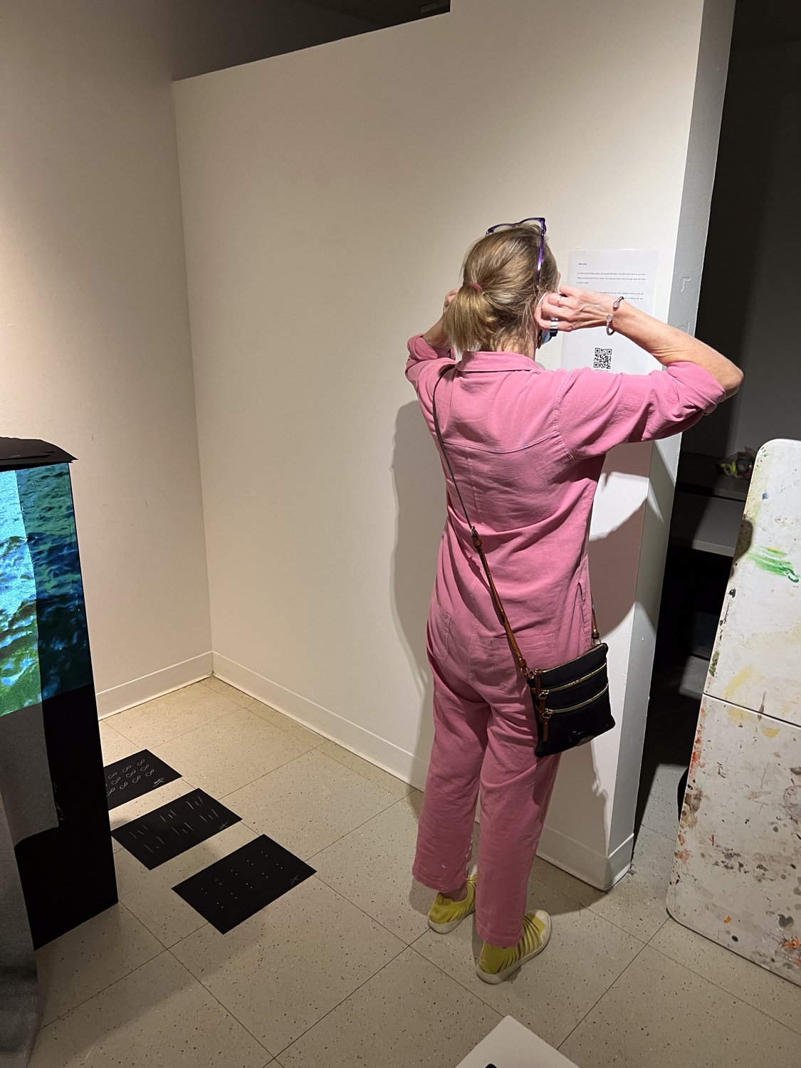 visitor reading the artist's wall text and scanning QR code, the take away, Fine Arts Studios, School of Visual Arts, New York, 2022