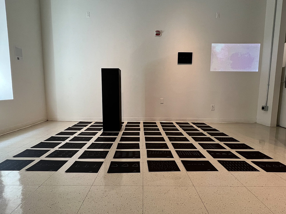 the giveaway, installation view at Fine Arts Studios, School of Visual Arts, New York, 2022 — wide view of floor pencil drawings with pedestal and projection