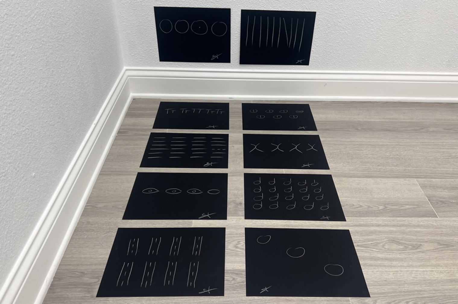 the giveaway, installation view at room in a room in a room, LOS/NR, La Jolla, 2024 — two chalk-on-canvas works on wall above eight floor pieces in a 4×2 grid